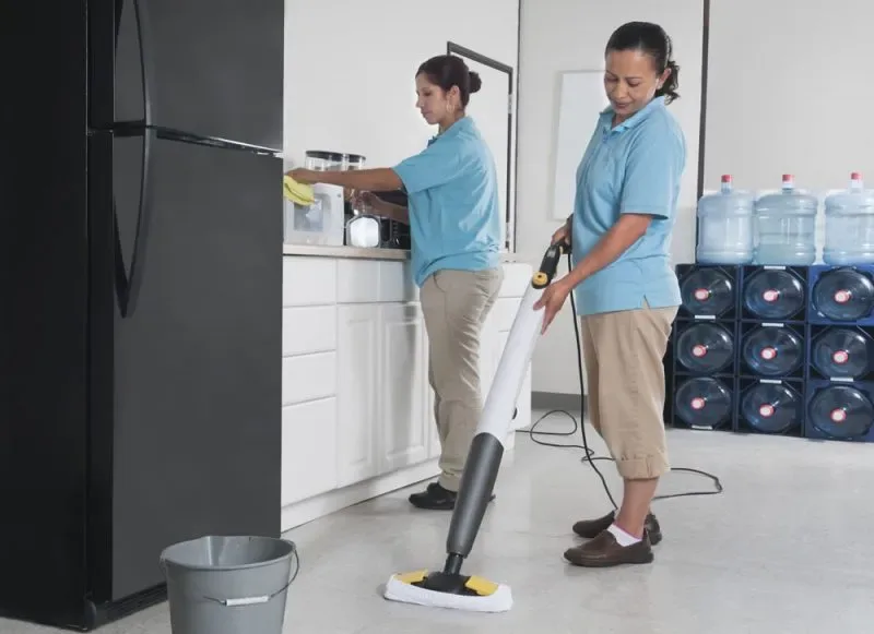 Twee schoonmaakmedewerkers reinigen een bedrijfskeuken