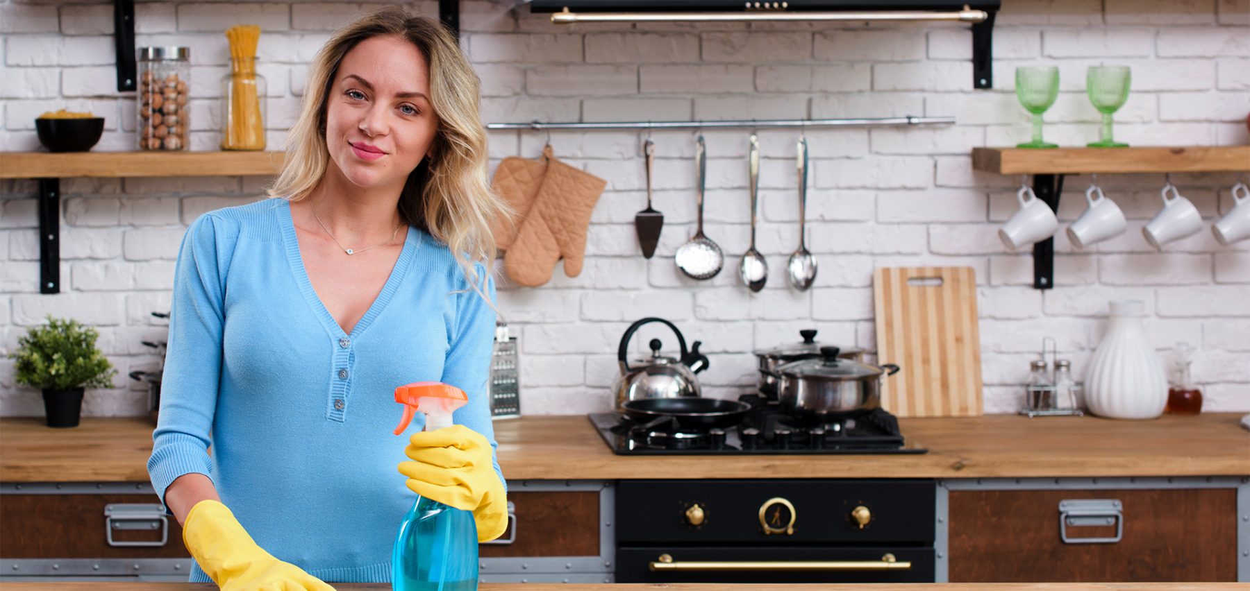 Schoonmaakmedewerker met reinigingsspray in een keuken